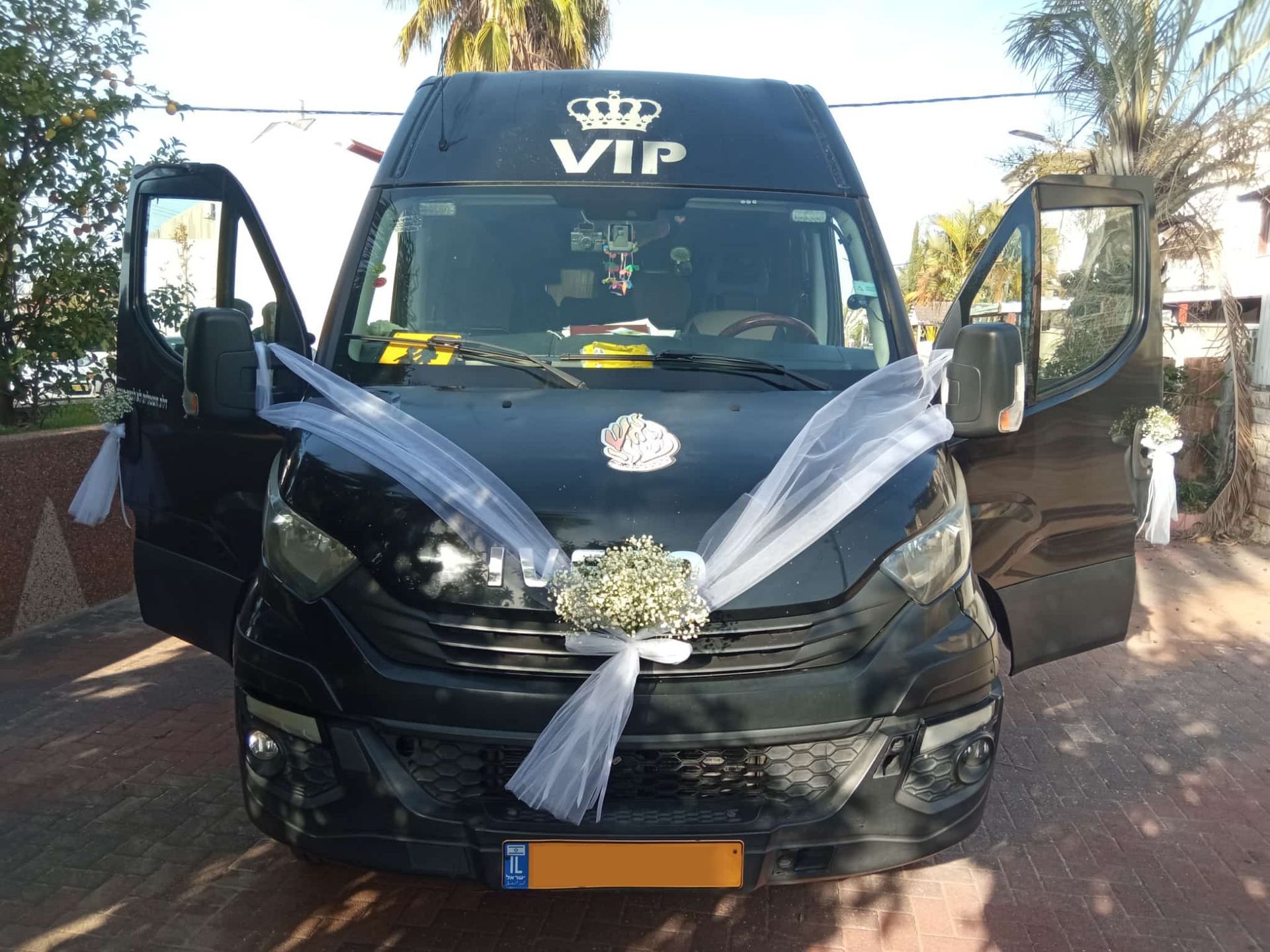 חזית של מיניבוס VIP שחור ומפואר מקושט בסרטים לבנים להסעות לאירועים וחתונות, כחלק משירותי מיניבוסים בראש העין.