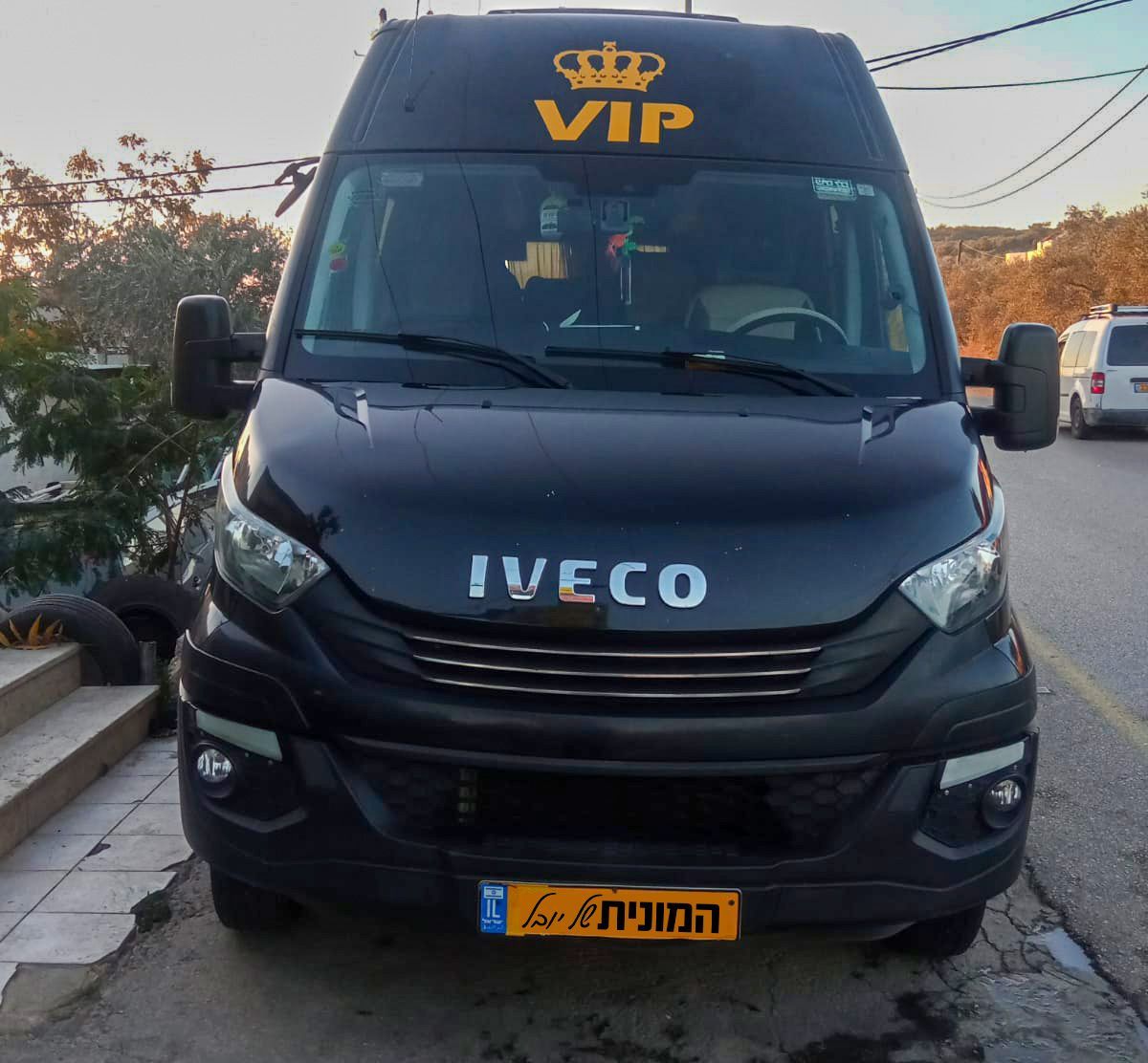 חזית של ואן IVECO שחור בעיצוב VIP ממותג עבור הסעות לנתבג. (מתאר ואן שחור עם סמל IVECO)