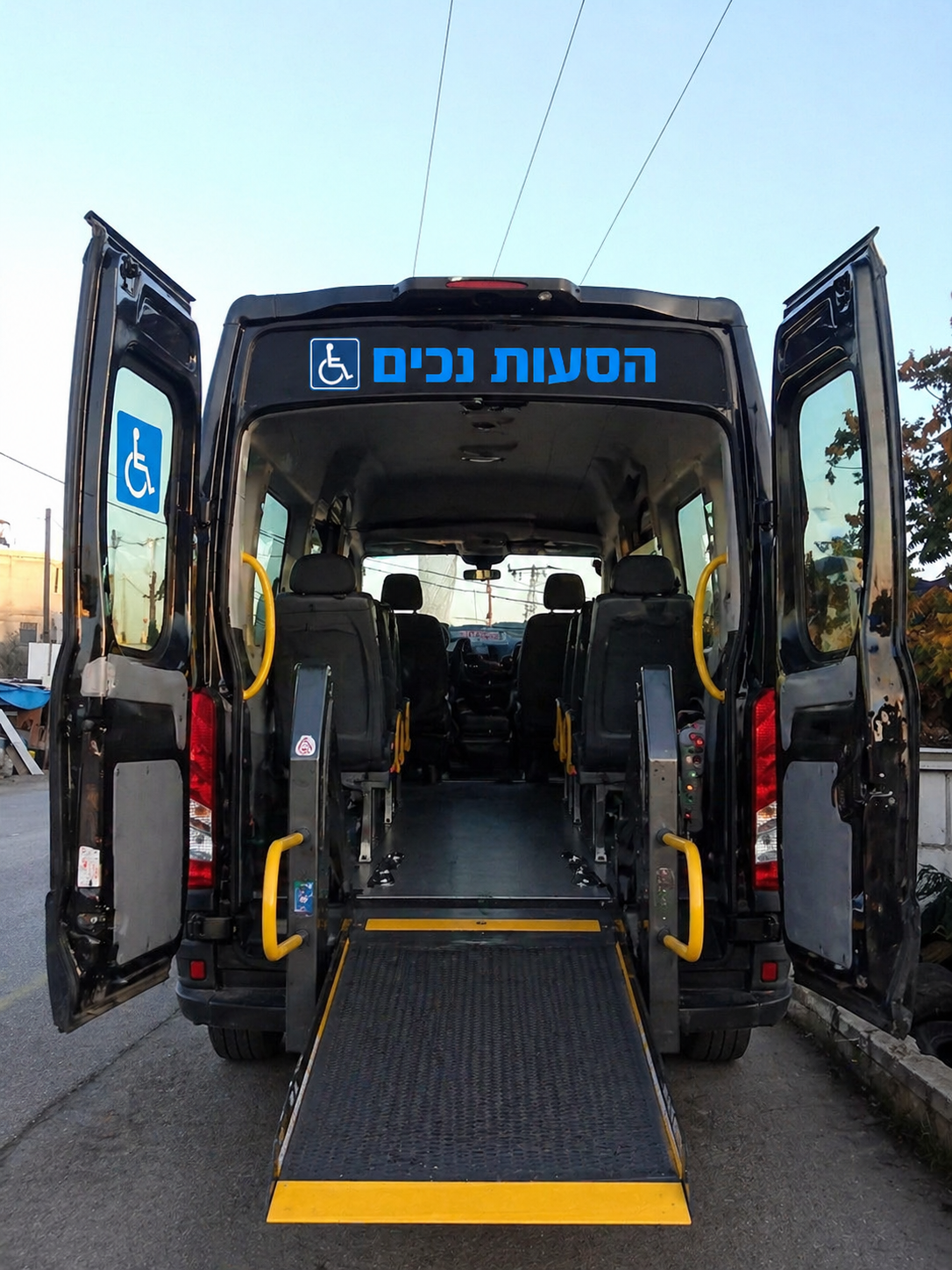 רכב מונגש שחור, צילום ישיר מאחור המציג דלתות פתוחות ורמפת עלייה לכיסאות גלגלים, כחלק משירות הסעת נכים בראש העין.