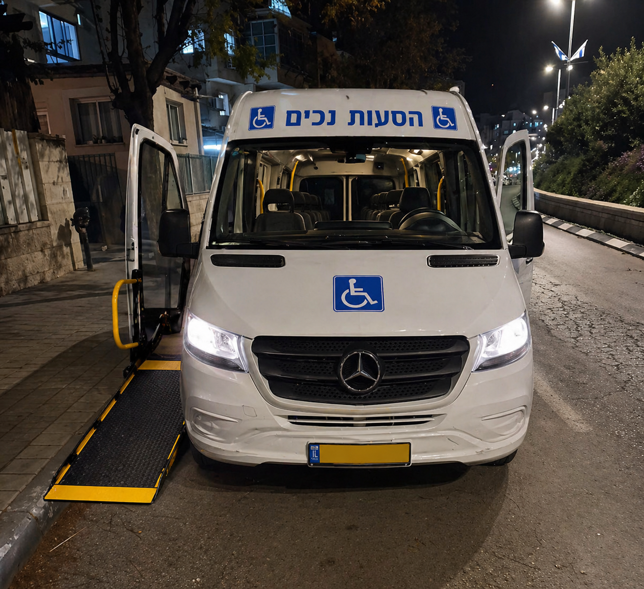 מבט מאחור על רכב הסעות שחור עם דלתות אחוריות פתוחות ומעלון נגישות מורד לכביש, למטרת הסעת נכים.