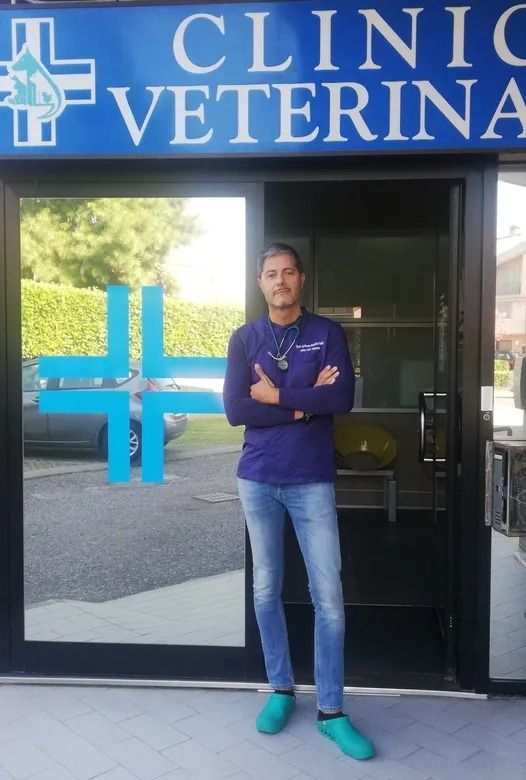 Persona in piedi con le braccia incrociate davanti all'ingresso di una clinica veterinaria.