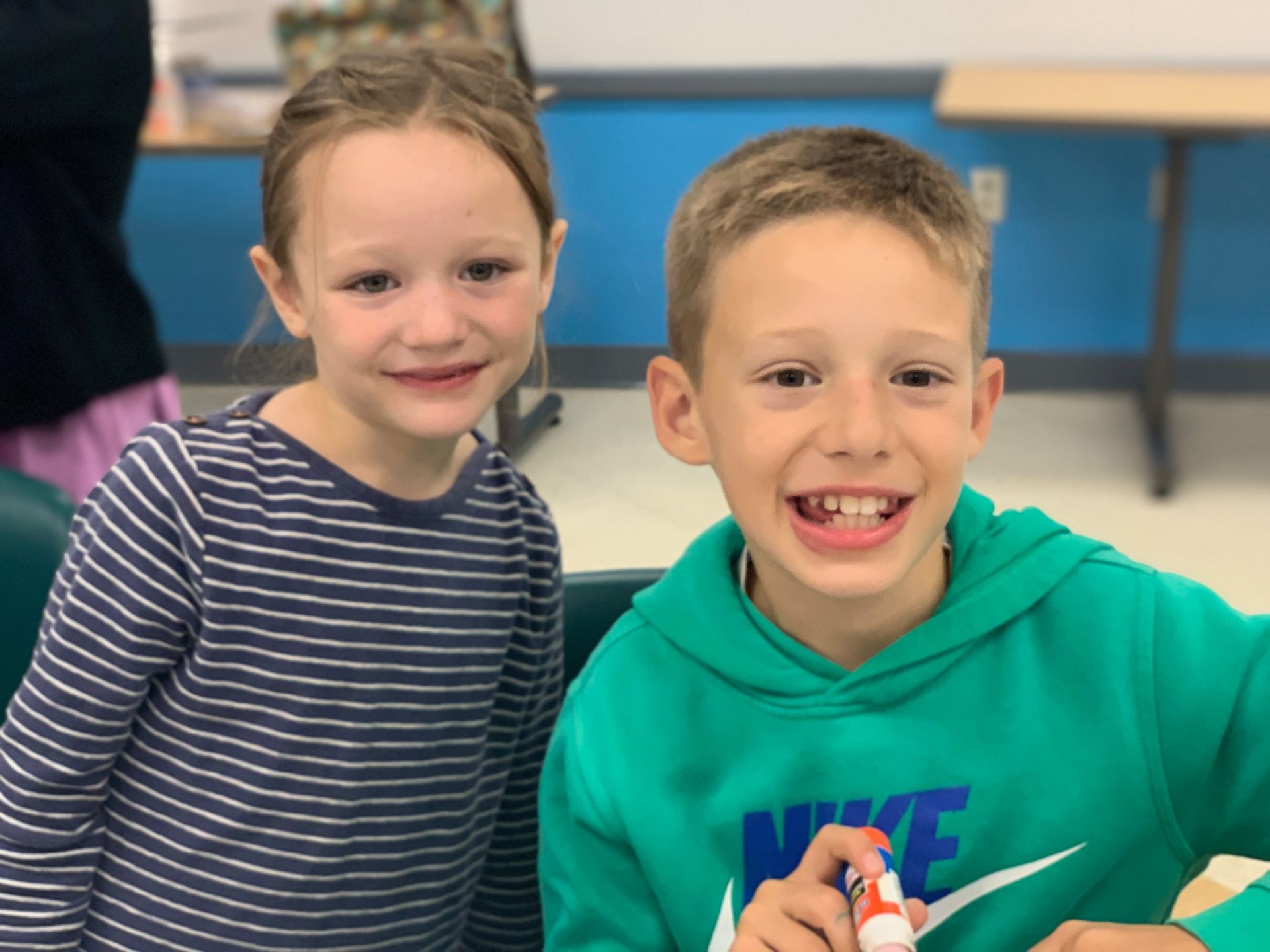 A boy sits next to a girl and both are smiling.