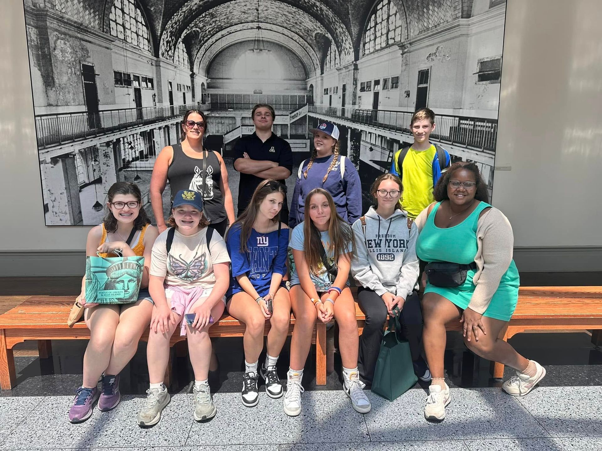 A group of teenagers are posing for a picture while sitting on a bench.