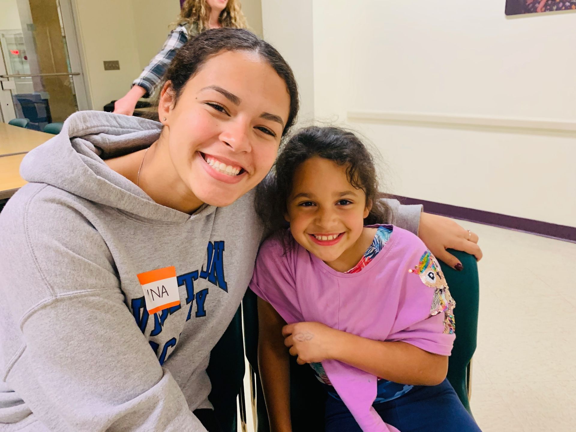 Two girls are posing for a picture, one is older and a volunteer.