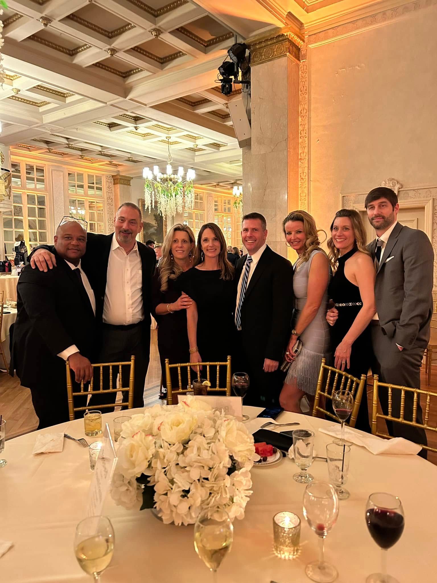 A group of people are posing for a picture at a fundraiser dinner table.