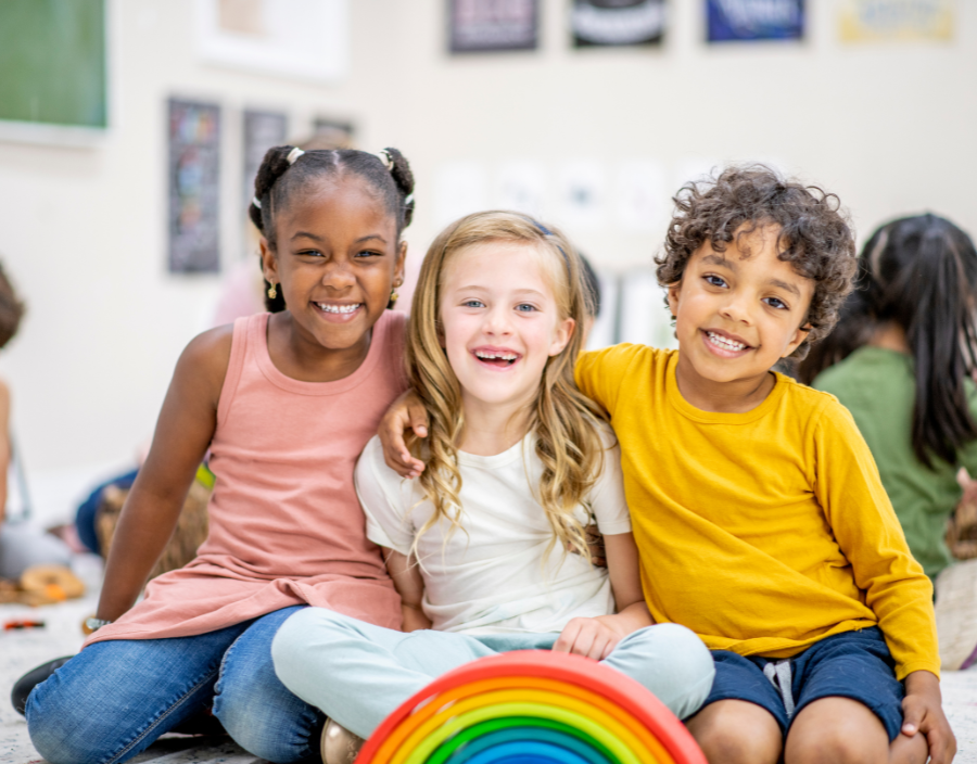 Three children are sitting on the floor with a rainbow.