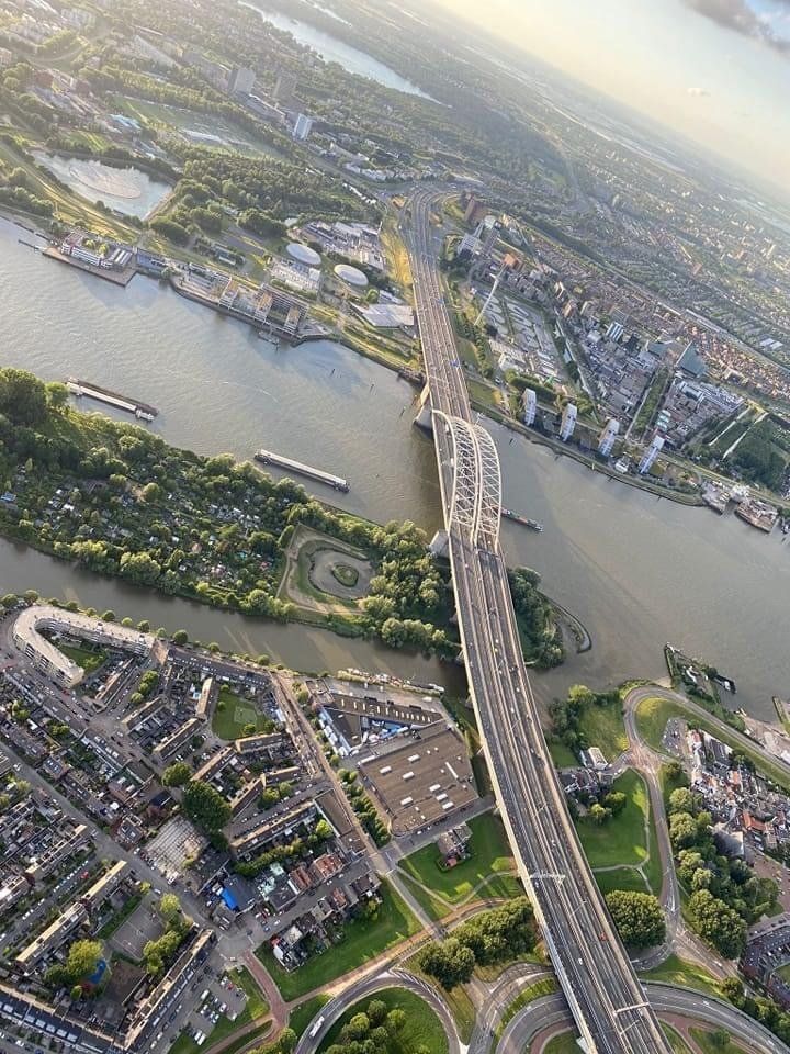 Luchtfoto van een lange brug over een rivier, die woonwijken met elkaar verbindt.