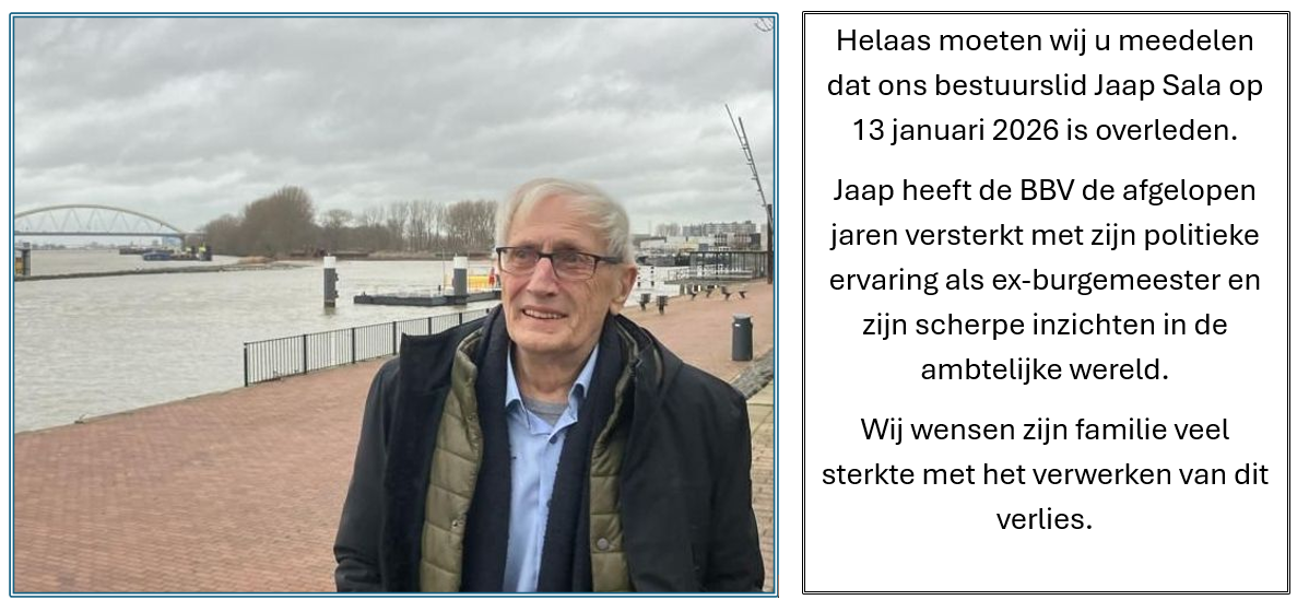 Een man met een bril staat op een pier naast het water. Naast hem staat tekst, mogelijk een gedenkteken.