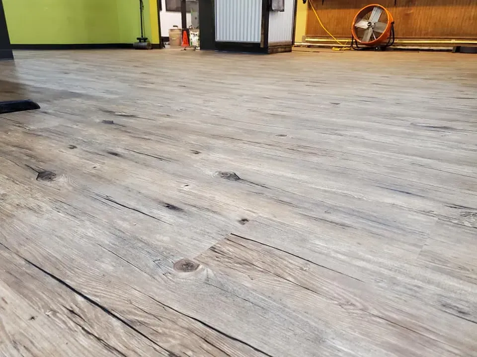 A wooden floor with a fan on it in a room.