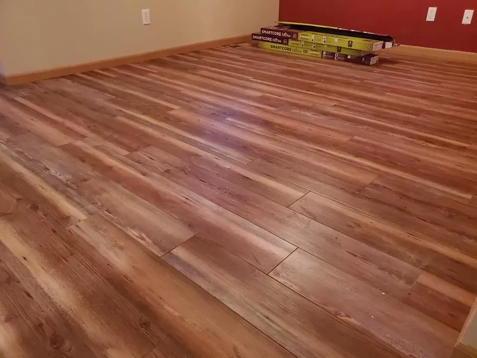 A room with a wooden floor and a stack of boxes on the floor.