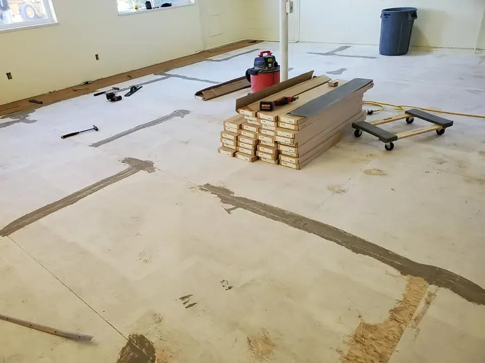 A room with a vacuum cleaner and a stack of wood on the floor.