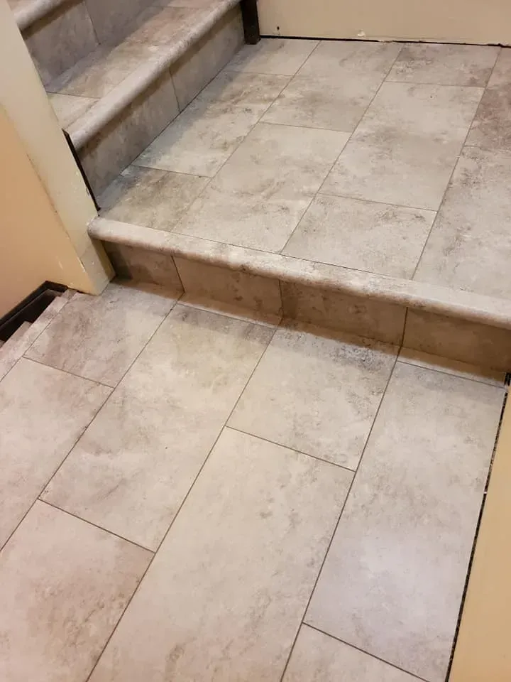 A close up of a tiled floor next to stairs.
