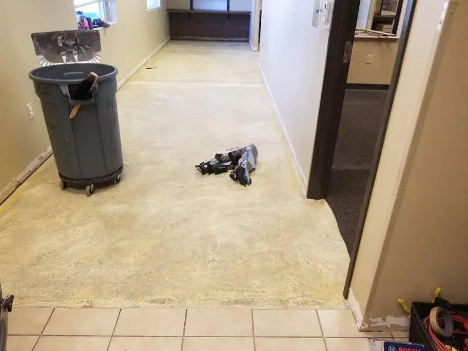 A hallway with a trash can and a pair of shoes on the floor.