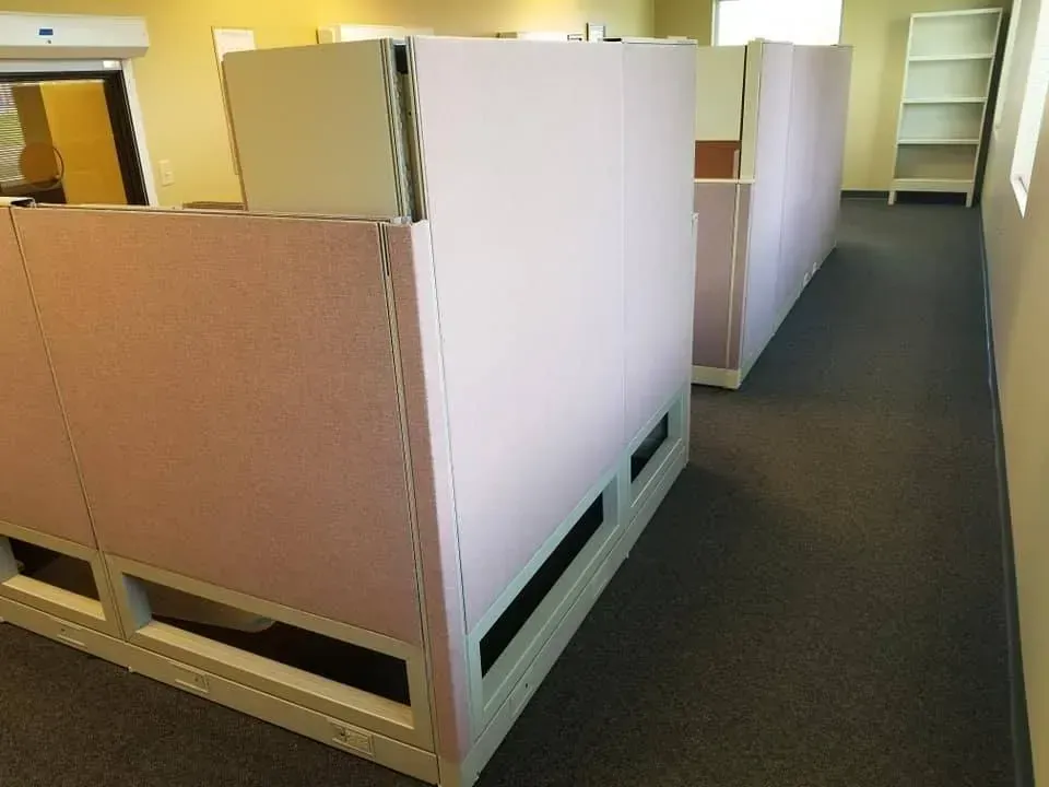 A row of cubicles in an office with a carpeted floor