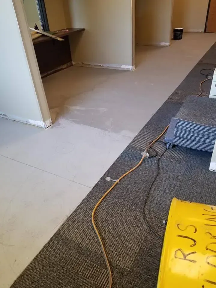 A room with a carpeted floor and a yellow bag on the floor.