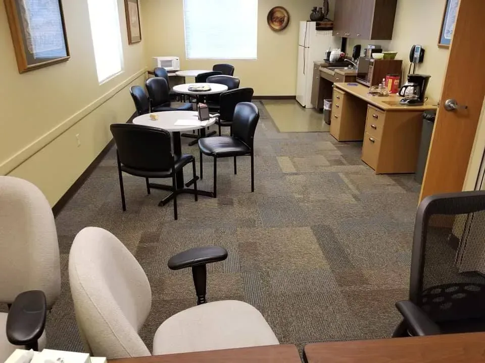 A room with tables and chairs and a refrigerator