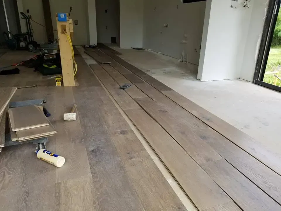 A room with a lot of wooden floors and a bottle of glue on the floor.