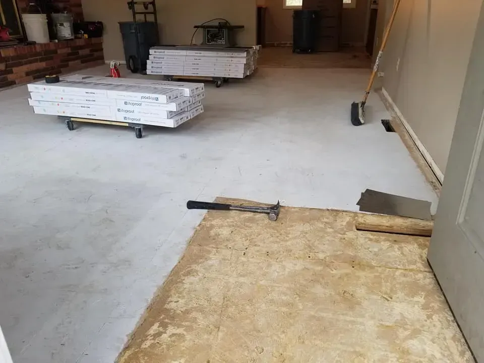 A hammer is sitting on a piece of plywood in a room.