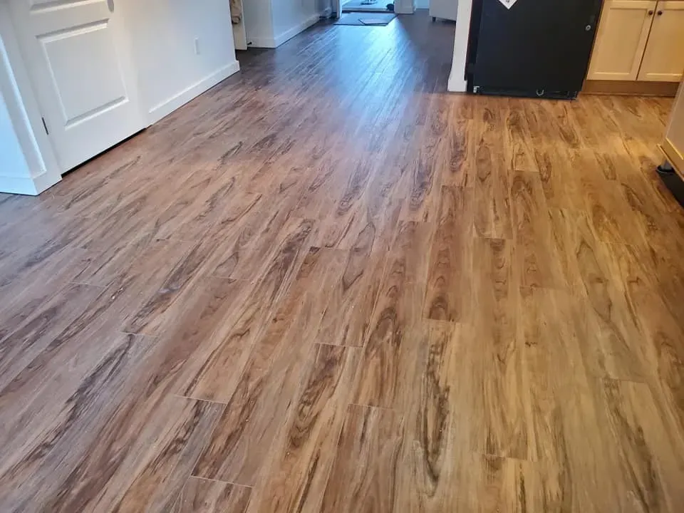 A kitchen with a wooden floor and a black refrigerator.