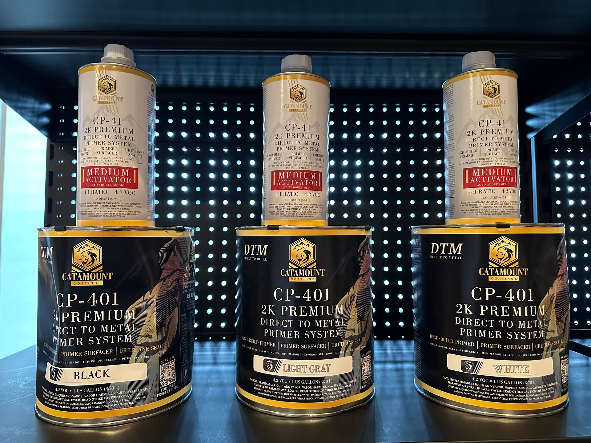 Three cans of paint are lined up on a shelf.
