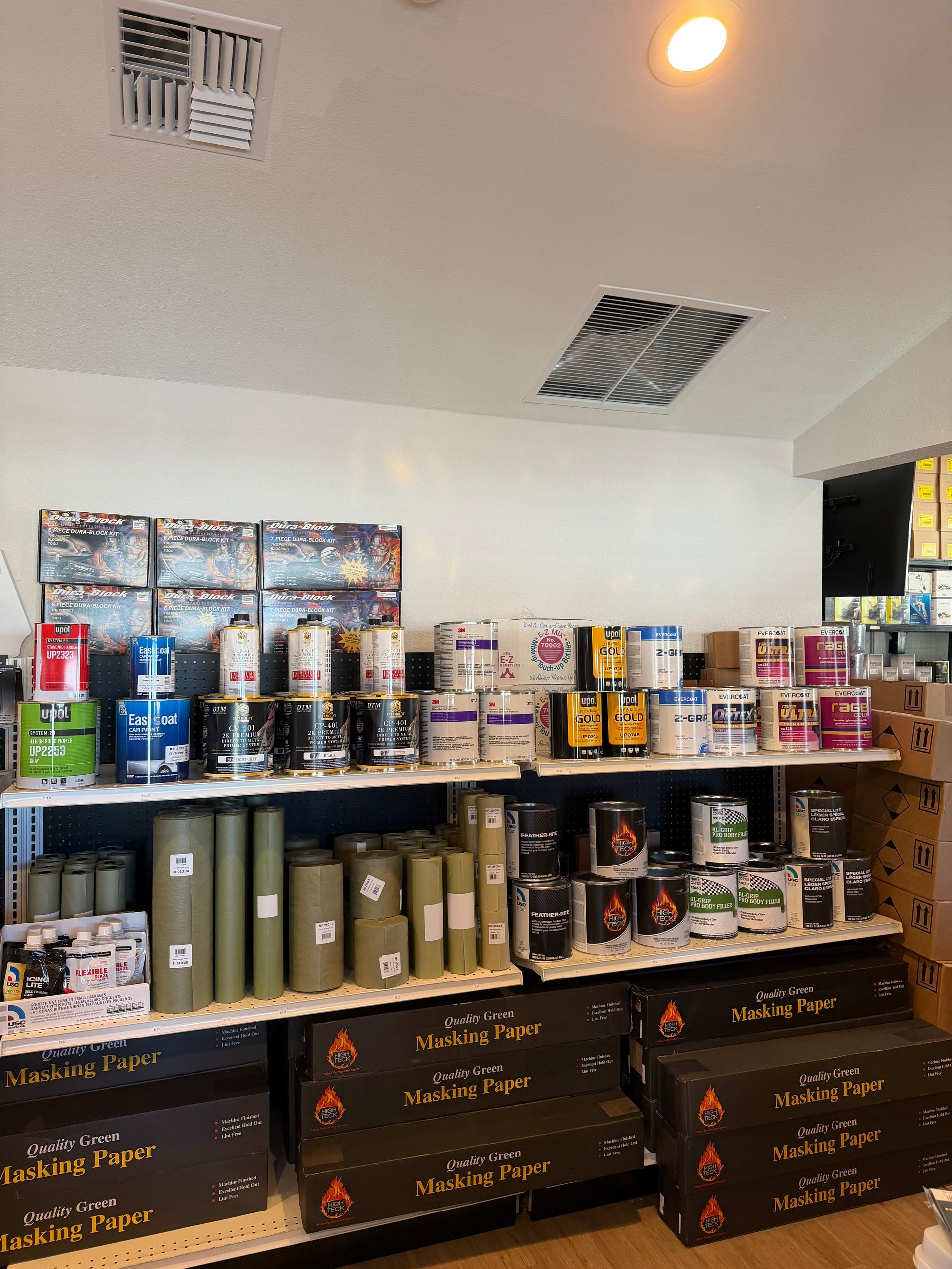 Shelves of paint cans and rolls of paper inside a store.