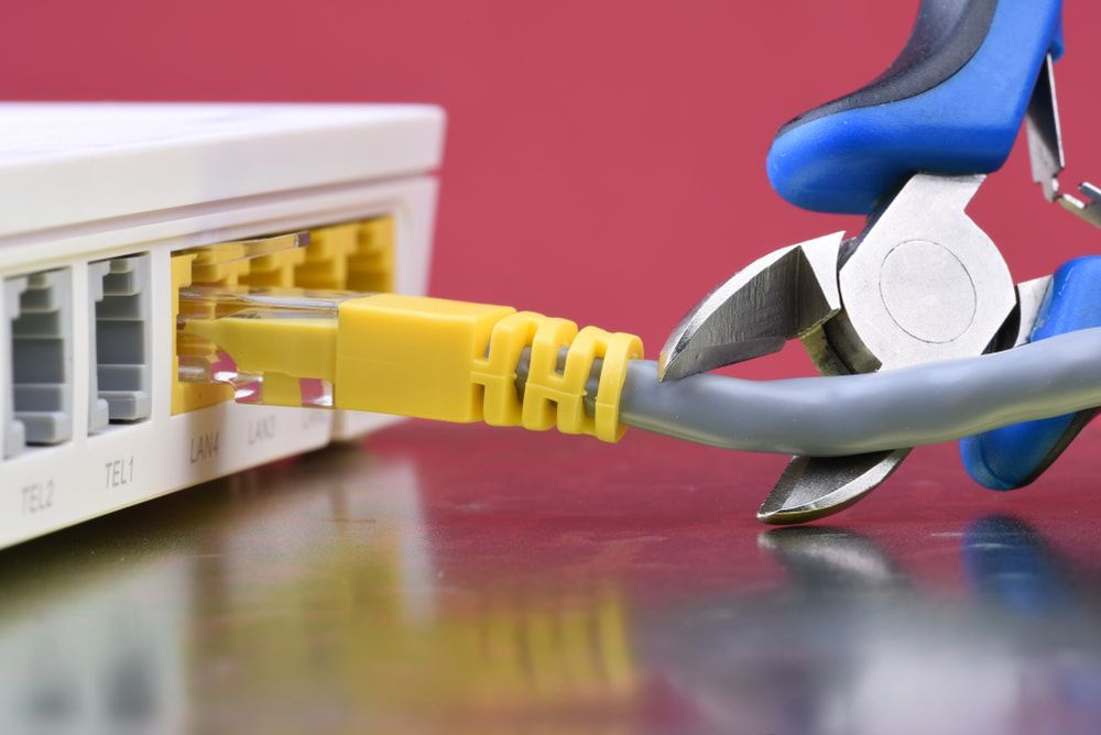 A Pair of Pliers Is Cutting a Cable Connected to A Router — Jason Wenta Electrical Services in Condon, QLD