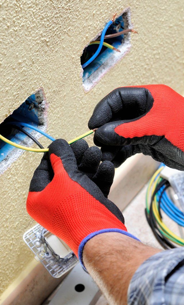 Electrician Work Prepares The Cable With Hands Protected by Gloves— Jason Wenta Electrical Services in Condon, QLD