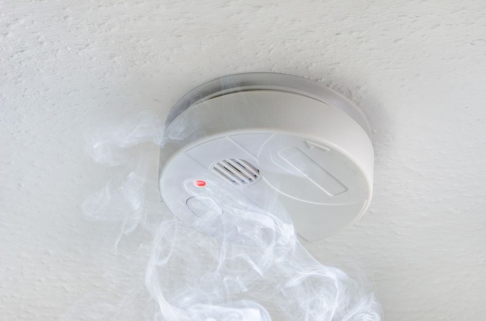 A Smoke Detector Is Hanging from The Ceiling and Smoke Is Coming out Of It — Jason Wenta Electrical Services in Condon, QLD