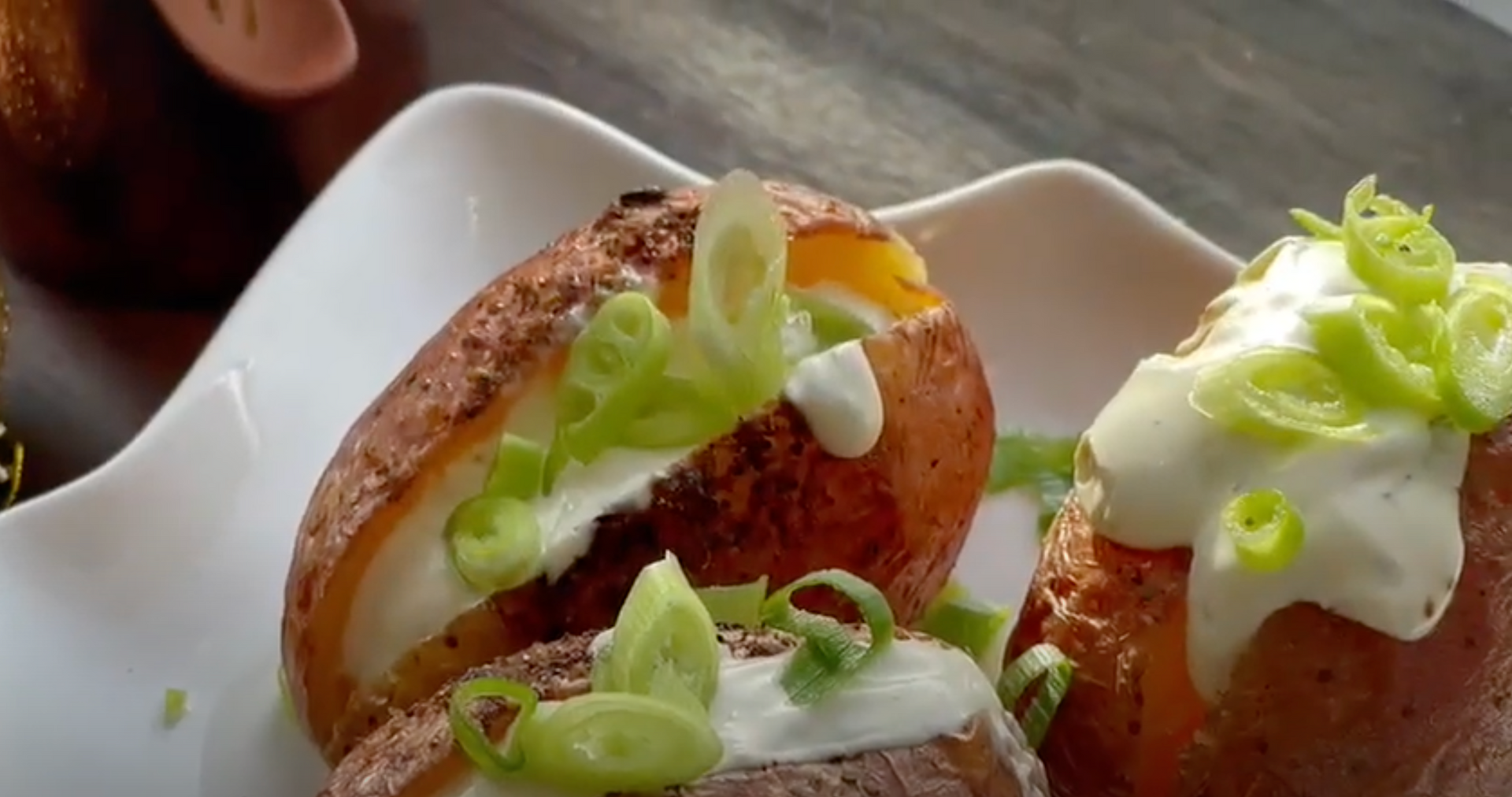 Gesneden brood besmeerd met romige spread en gegarneerd met groene ui op een wit bord.