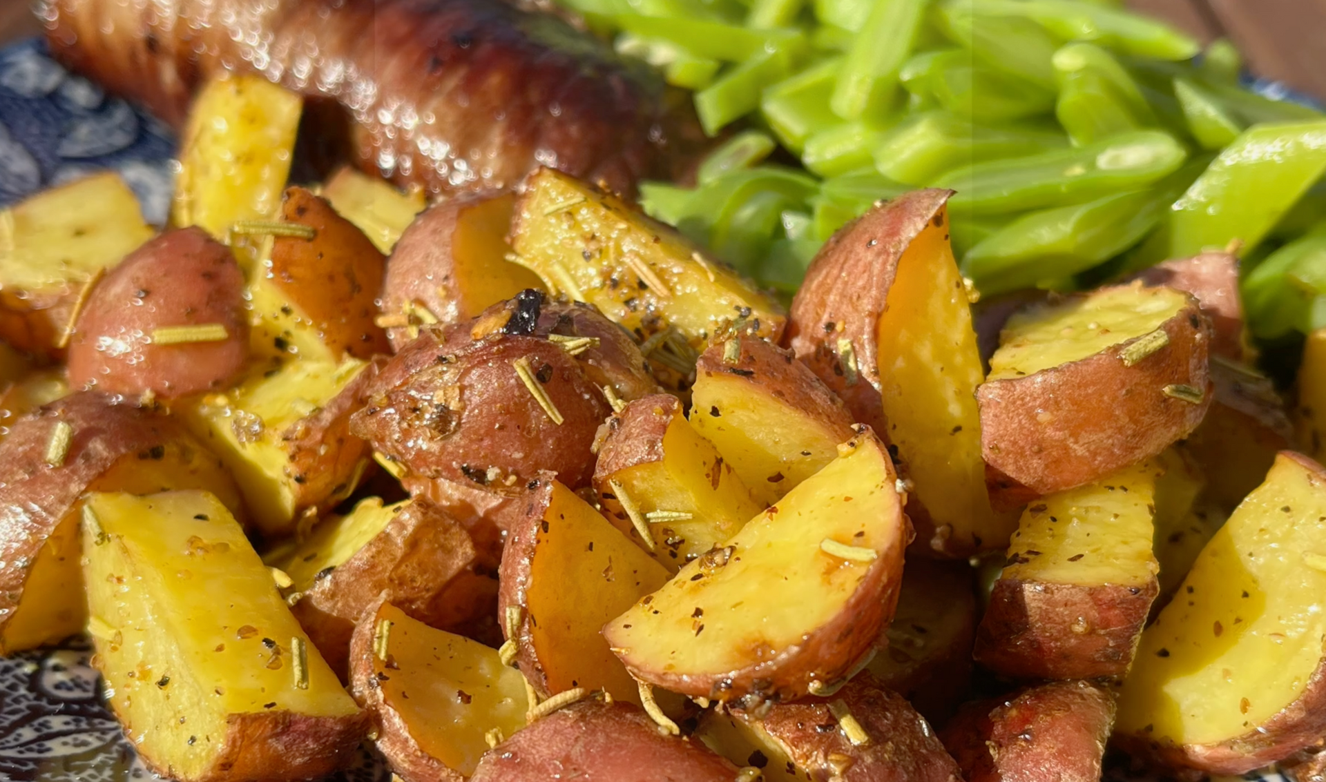 Geroosterde aardappelen met kruiden, naast sperziebonen op een bord.