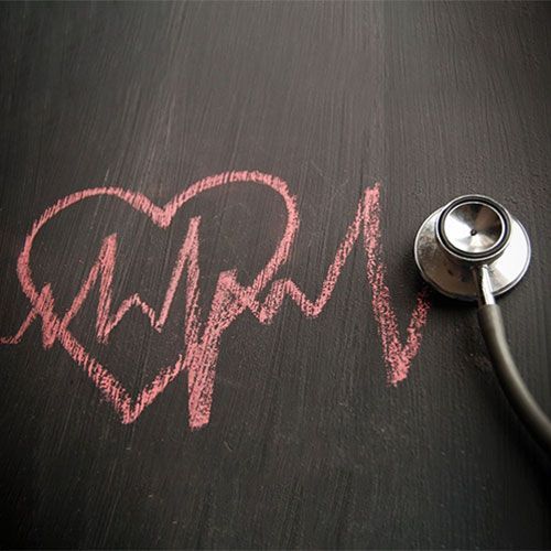 Heart drawing with an EKG line and stethoscope on a black surface.