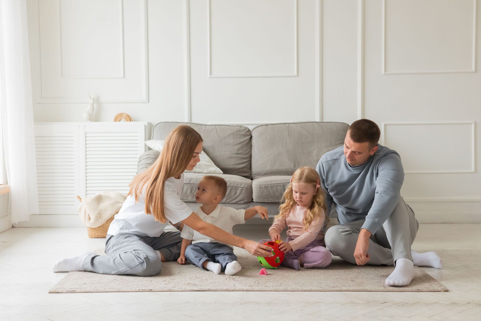 Young Colorado parents playing with their two small children at home, protected by life insurance.