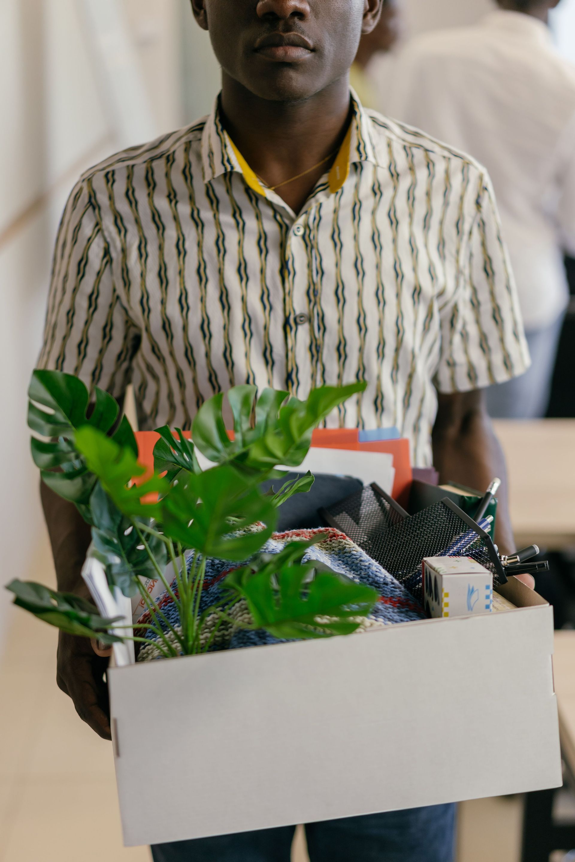 Professional leaving a job with a box of belongings, the kind of coverage gap short-term plans address.