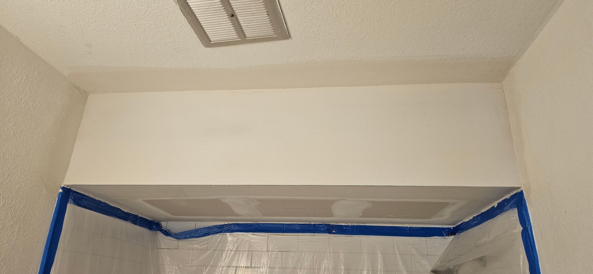 A view of a painted room during renovations; tape and plastic protect the lower area.