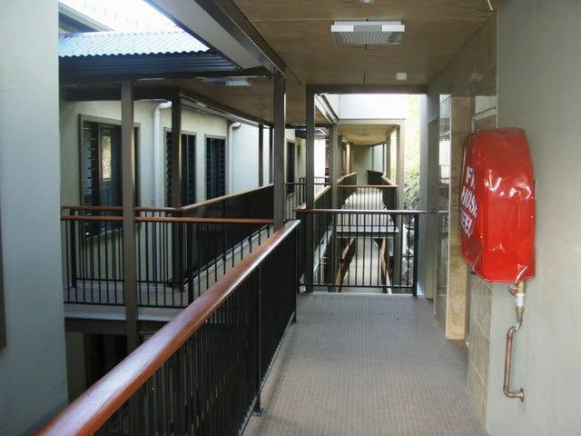 Indoor corridor with black railings and a red fire extinguisher cabinet on the wall