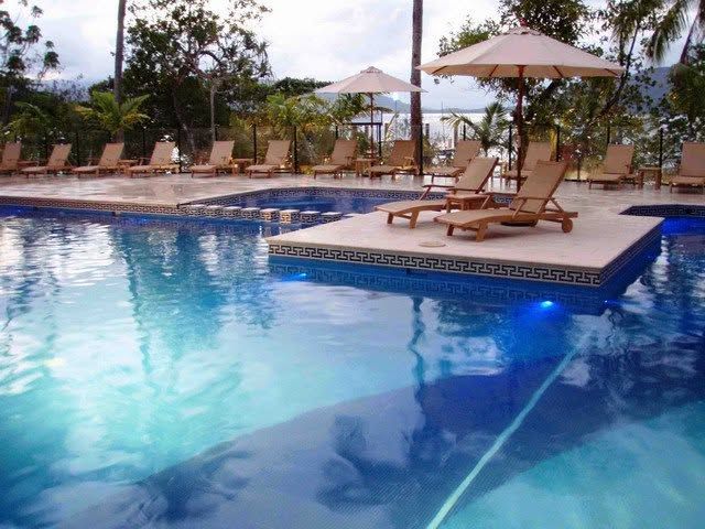 Resort pool with lounge chairs and umbrellas beside clear blue water