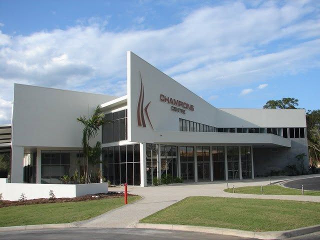 Modern white building with large glass windows and a curved facade under a blue sky