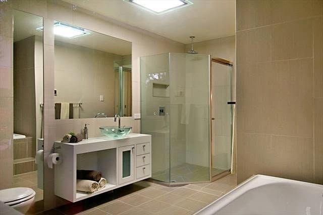 Modern beige bathroom with a double sink vanity, glass shower, and bathtub
