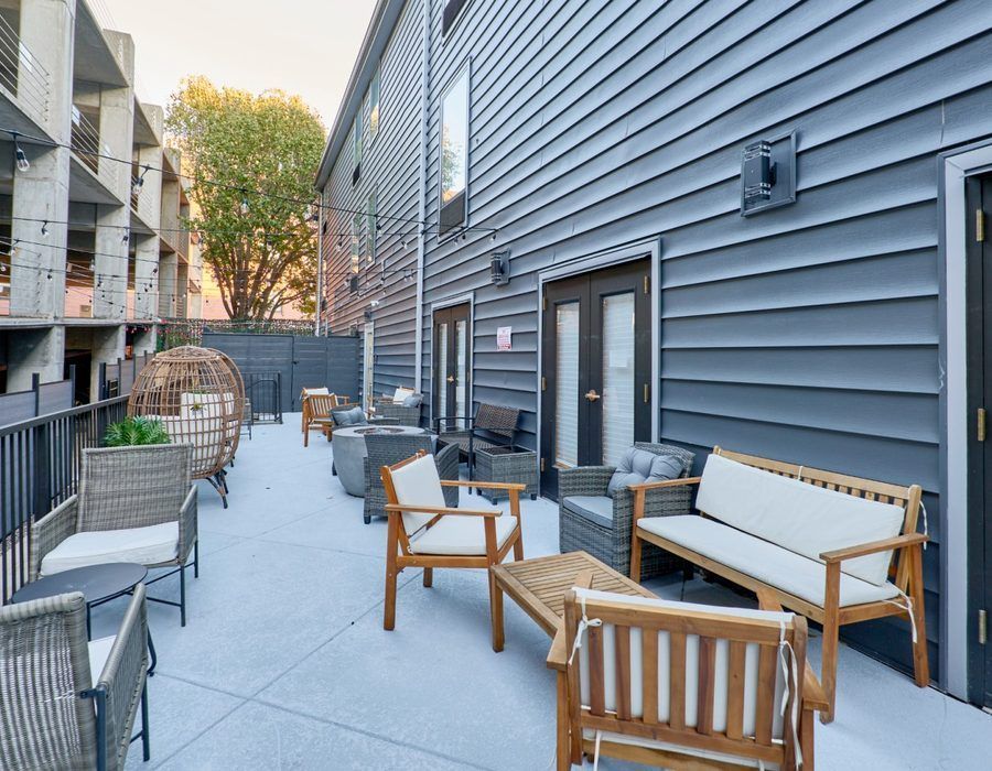 Modern patio with wood and metal seating beside a gray-sided building.