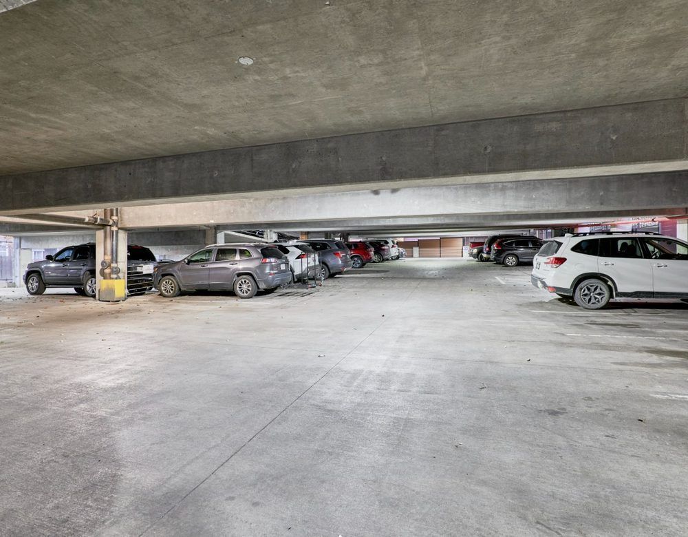 Low-ceiling parking garage with several parked cars in rows