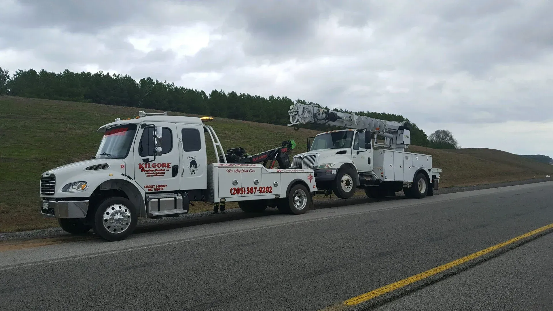 Two tow trucks are parked on the side of the road.