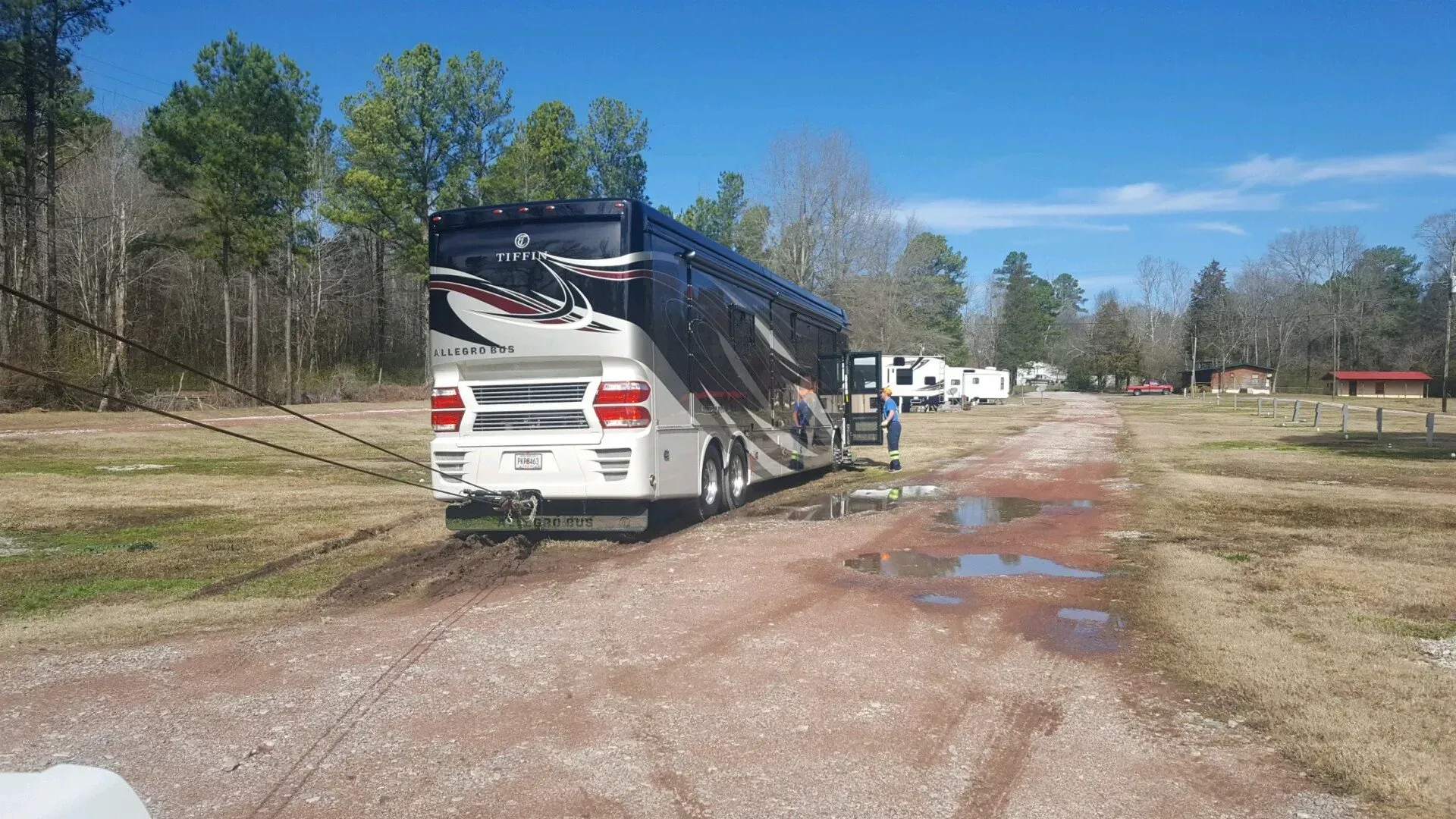 A large rv is parked on the side of a dirt road.