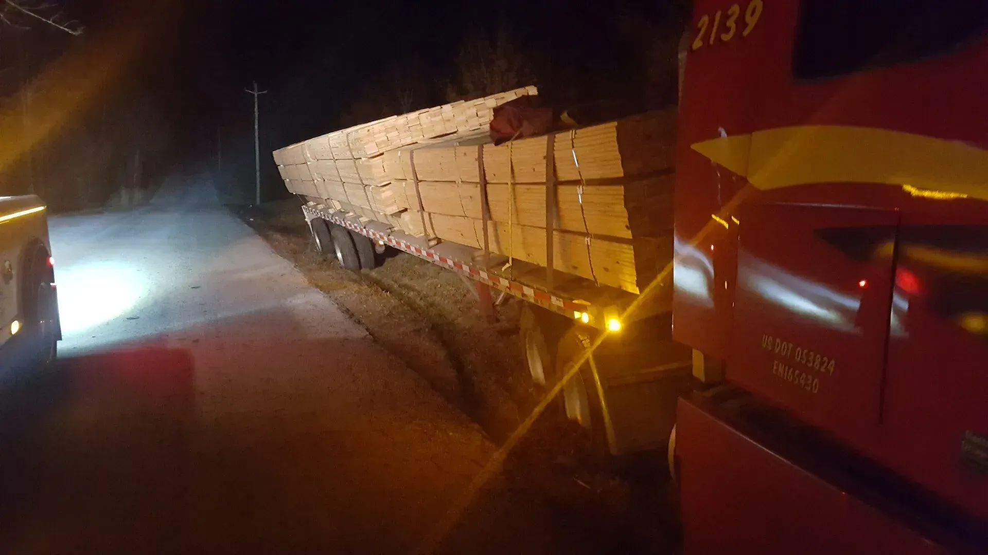 A big red truck carrying wood.