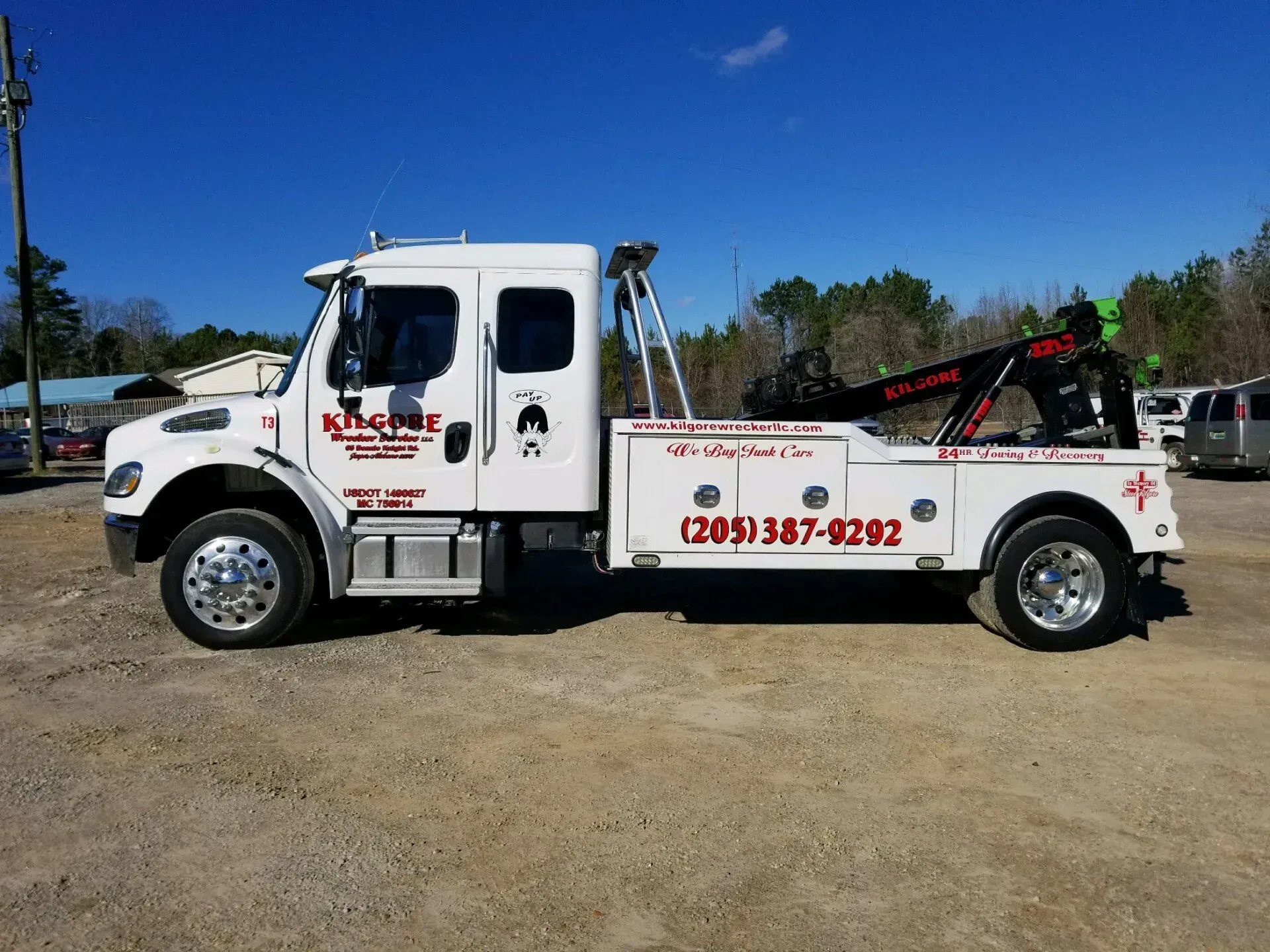 A white tow truck is parked in a dirt lot.