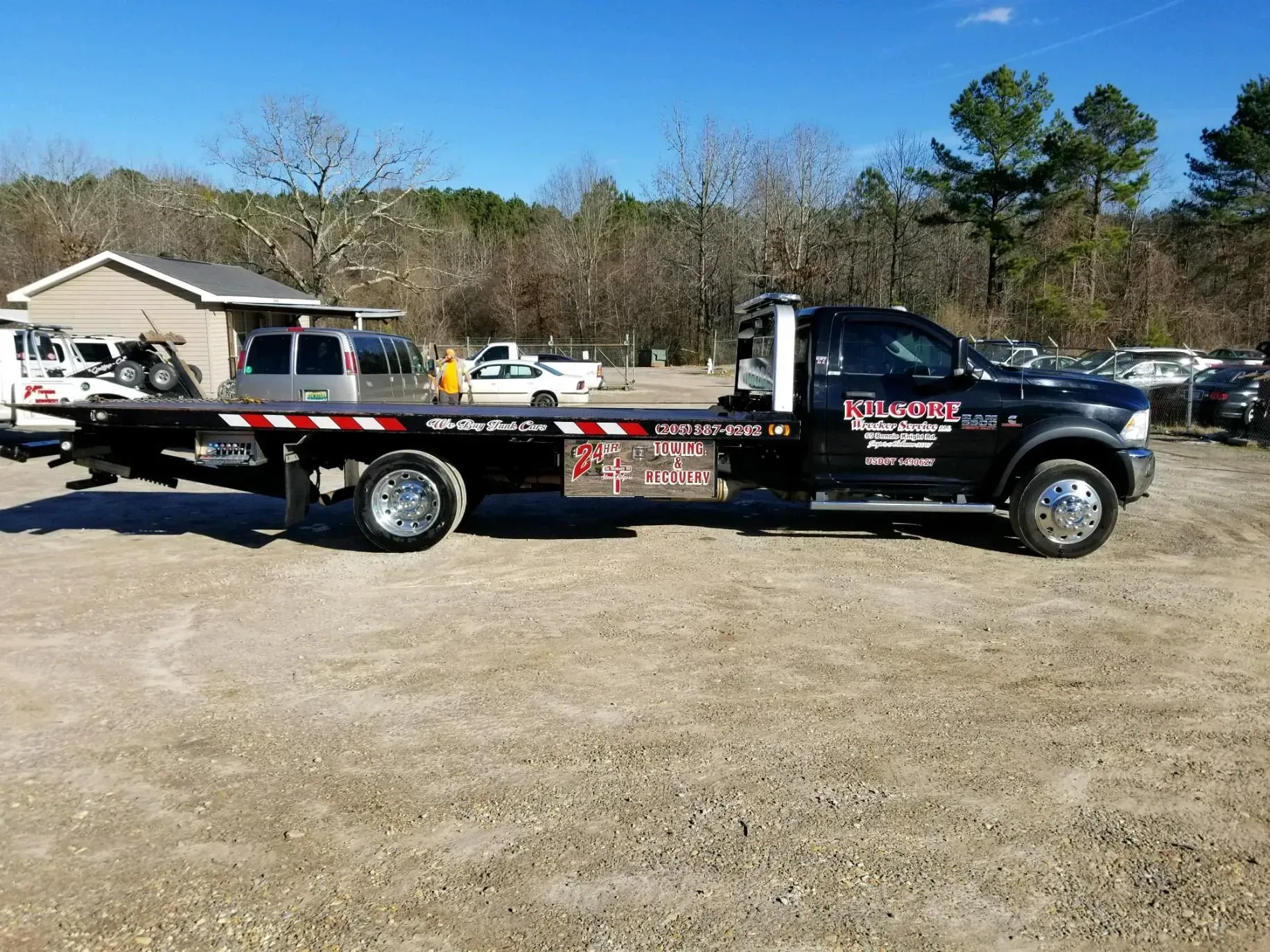 A black tow truck is parked in a gravel lot.