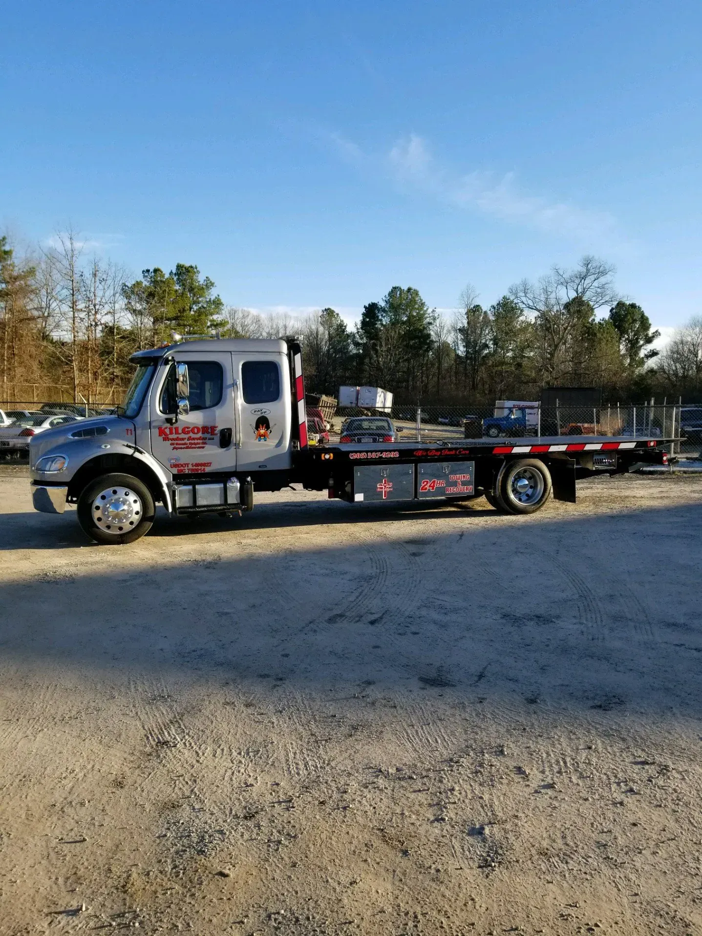 A tow truck is parked in a gravel lot.