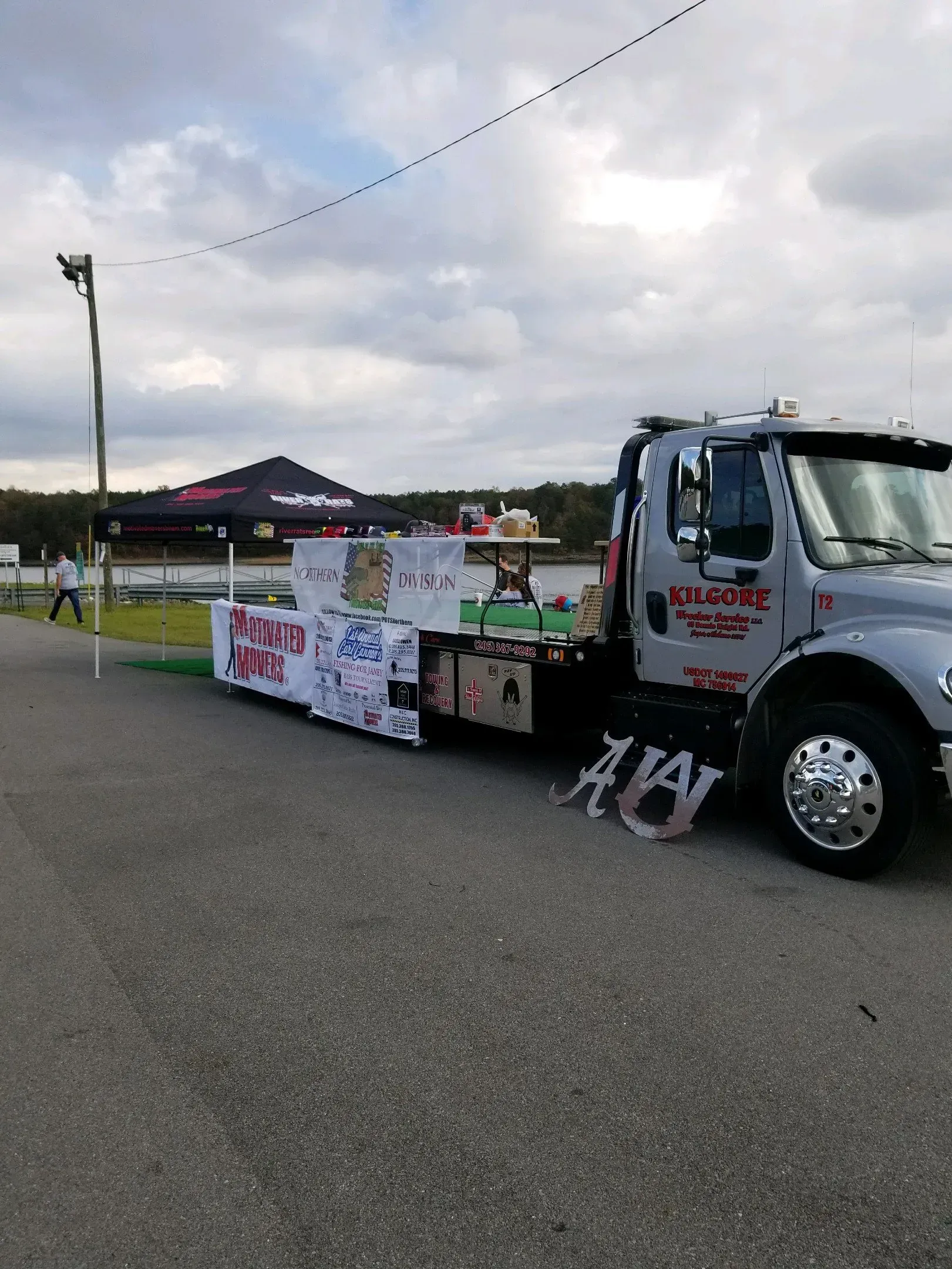 A tow truck is parked on the side of the road next to a tent.