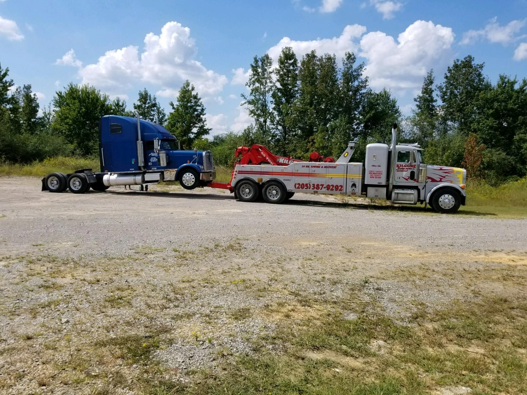 A blue semi truck is being towed by a tow truck.