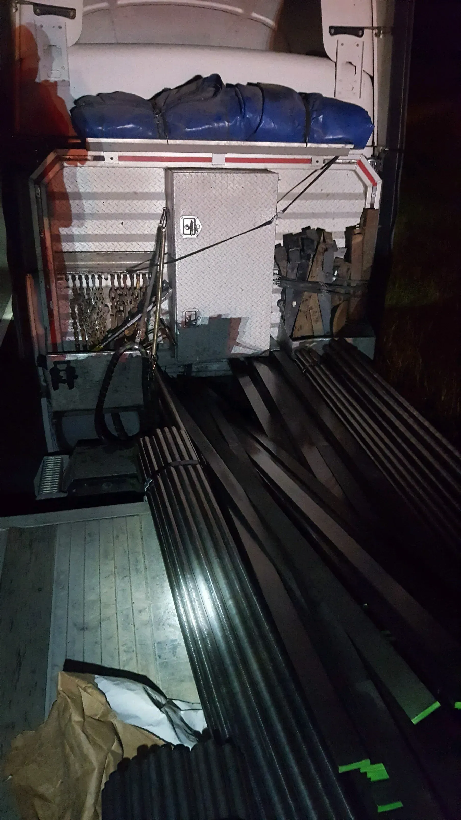 A bunch of metal pipes are stacked on top of each other in a warehouse.