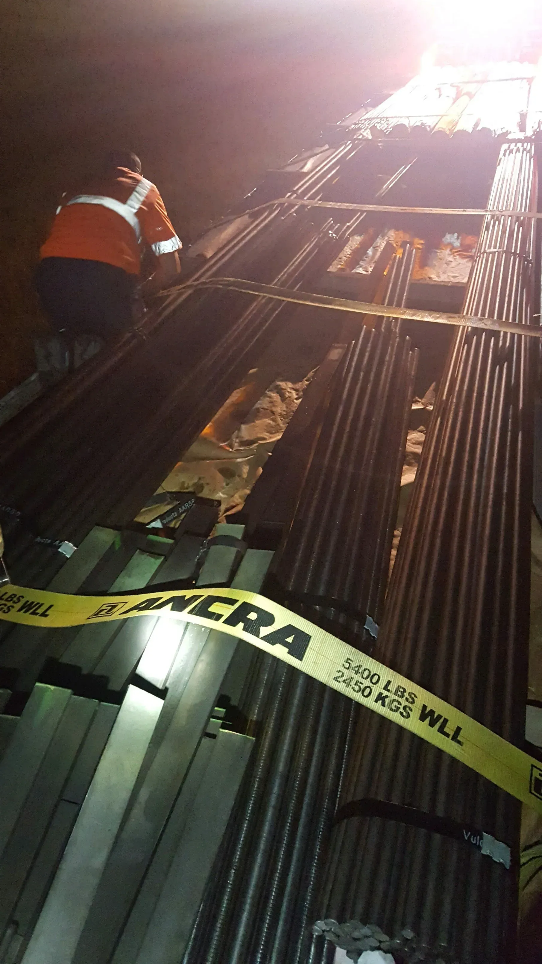 A man is standing on top of a pile of metal pipes.